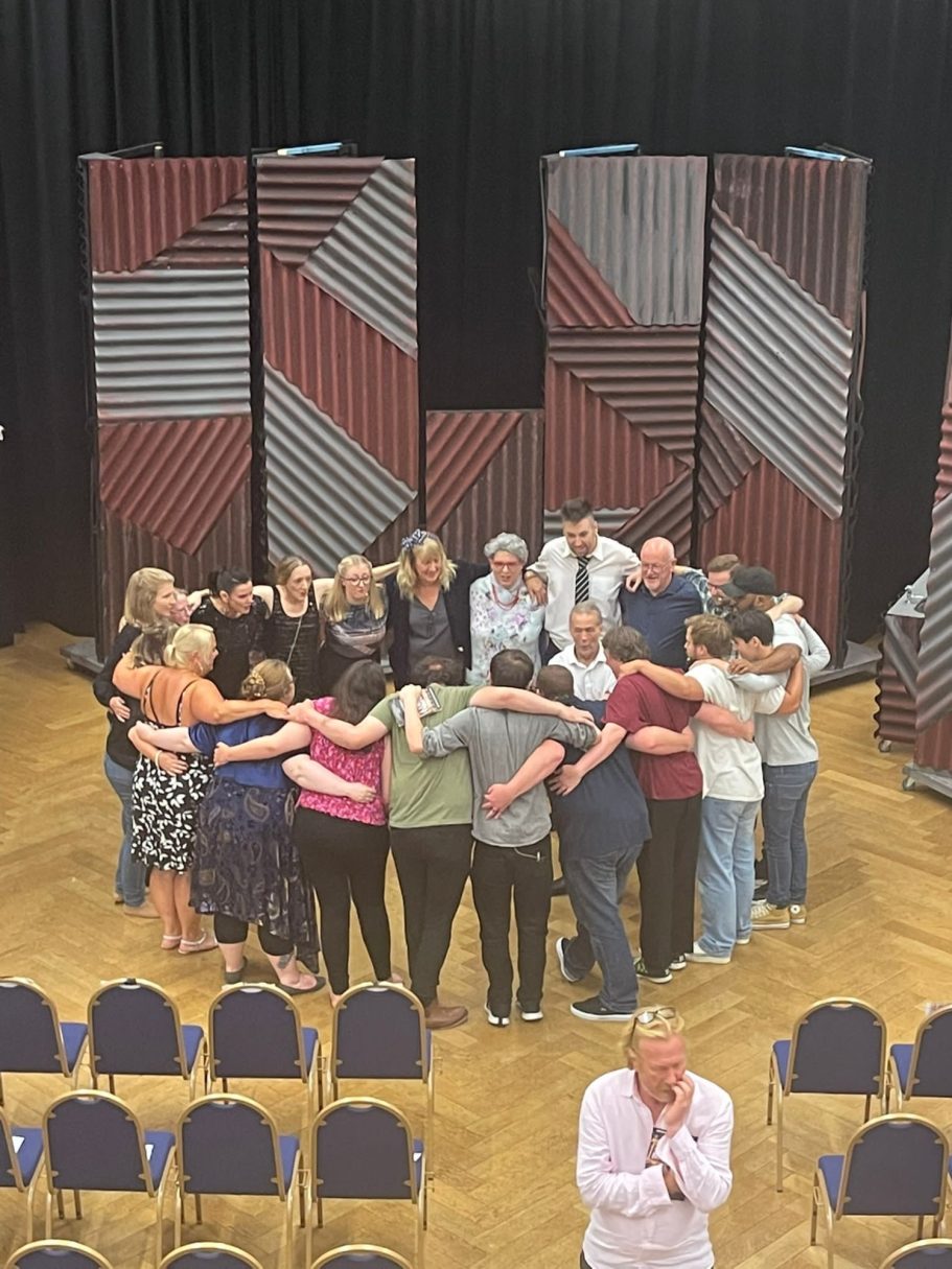 A group of people standing closely together in a circle on a stage.