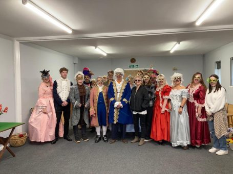 Group of people dressed in historical costumes, posing together indoors.