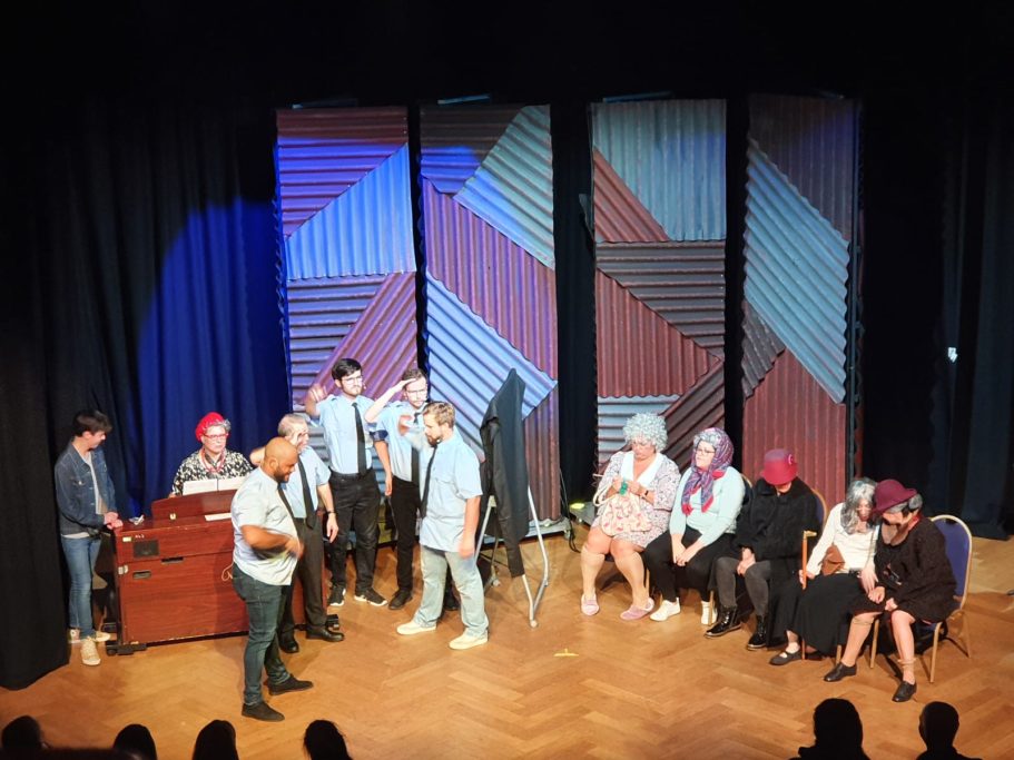 A group of performers on stage, engaging the audience in a lively theatrical setting.