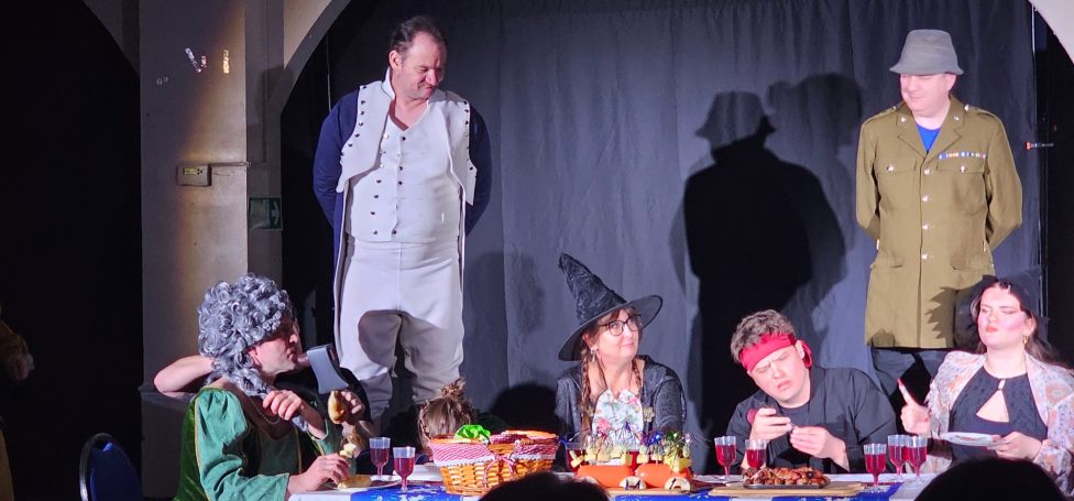 Adult Drama Classes A theatrical scene with actors in costumes performing at a table.