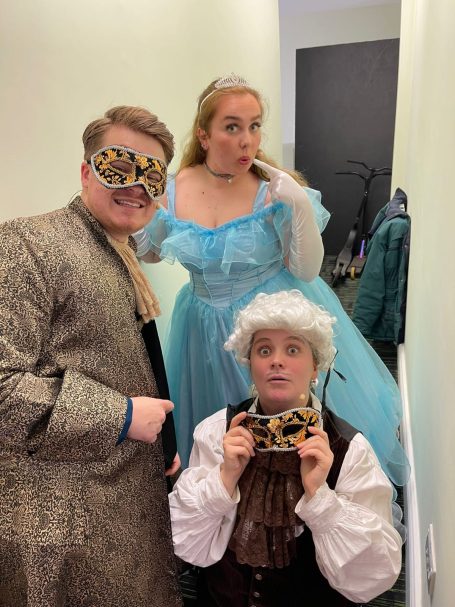 Three individuals in costumes: a prince, a princess in blue, and a character with white hair.