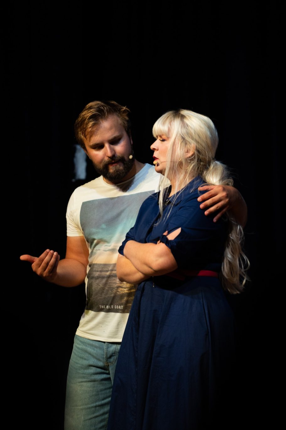 A man and woman perform a dramatic scene on stage, with emotional expressions.