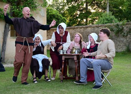 A group of people in historical costumes enjoying a lively gathering outdoors.